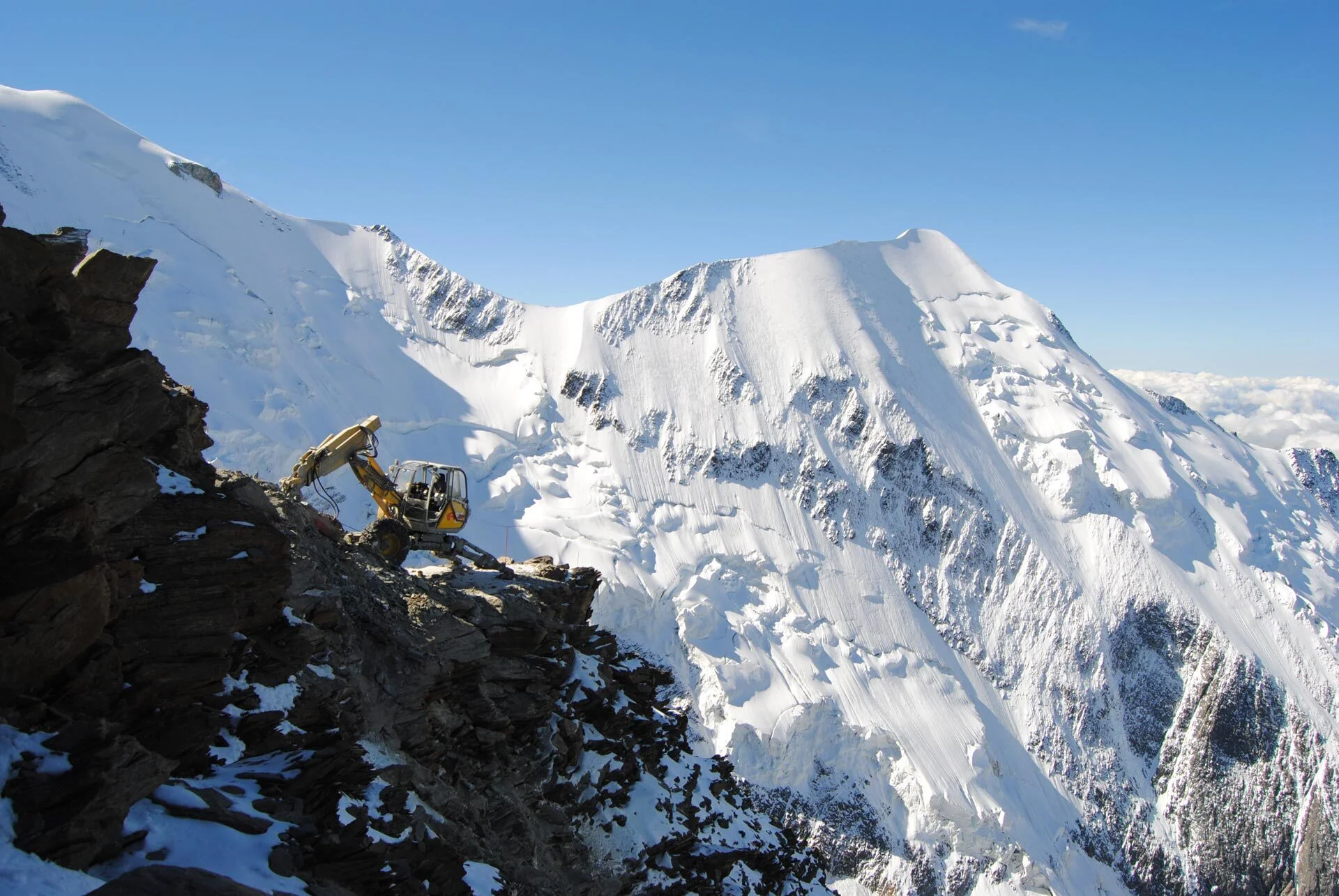 Image de fond montrant une pelle araignée sur une montagne avec le mont blanc en fond